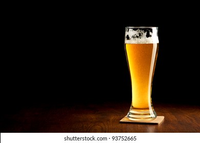 Beer Into Glass On A Black And Wooden Table