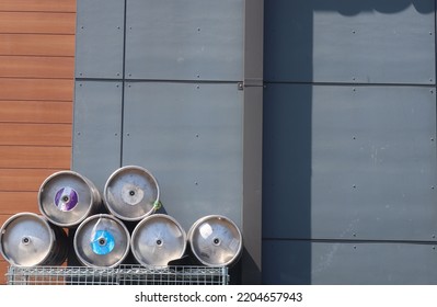 Beer Kegs Stacked Before Gray Alley Wall.