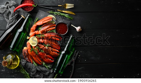 Beer party. Beer, snacks and\
lobster claws on a black background. Rustic style. Seafood\
delicacies.