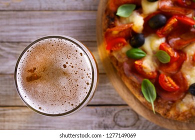 Beer and pizza on wooden plate. Ale and  snack. Overhead, horizontal - Powered by Shutterstock