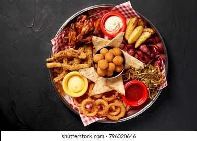 The beer plate with spicy chicken wings, calamari rings, fries onion rings, cheese balls, breaded, tartar sauce and garlic - Shutterstock ID 796320646