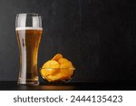 Beer and potato chips. Over dark background with copy space