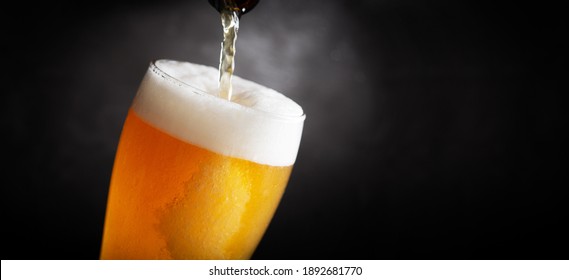 beer pouring into glass from bottle on a dark background - Powered by Shutterstock