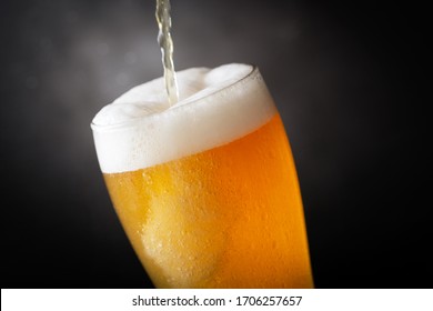 Beer Pouring Into Glass On Dark Background