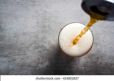 Beer pouring out of a can into a glass on a concrete table