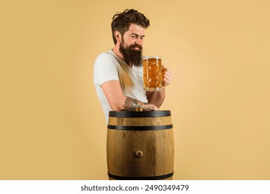 Beer pub. Bearded hipster tasting craft beer at cafe, bar or restaurant. Handsome male drinking ale on party. Brewing. Beer time. Alcohol and Oktoberfest celebration. Smiling guy with mug of beer - Powered by Shutterstock