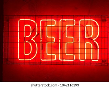 Beer red neon sign fixed to a wall behind metal cage - Powered by Shutterstock