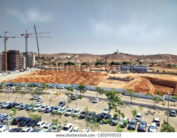 Beer Sheva, Israel-August 29, 2018: A huge\
public parking lot at front view and ground works in foundation\
pits in progress at the back view. Advanced Technologies Park is\
under construction.