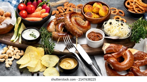 Beer And Snack Set. Oktoberfest Food Frame Concept. Variety Of  Grilled Sausages, Fried Potatoes, Chips, Vegetables, German Pretzel Pastry, Almonds And Sauces On Dark Wooden Background. Top View.