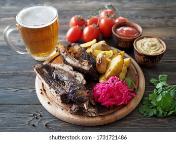 Beer and snacks on a rustic table - grilled ribs, tomato sauce, mustard, potatoes, sauerkraut.