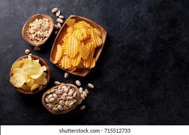 Beer Snacks On Stone Table. Various Nuts, Potato Chips. Top View With Copy Space