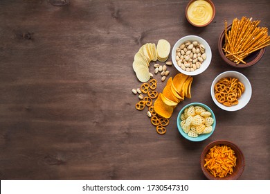Beer snacks on a wooden table. Beer with pretzels and various snacks. View from above. Copy space. Banner.