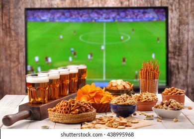 Beer and snacks set on football match tv background 