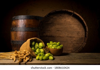 Beer. Still life with Vintage beer barrel and glass light beer. Fresh amber beer concept. Green hop and gold barley on wooden table. Ingredients for brewery. Brewing traditions