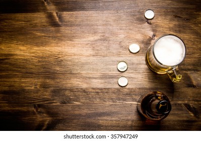 Beer style- bottle, beer in the glass and covers on wooden table. Free space for text. Top view - Shutterstock ID 357947249
