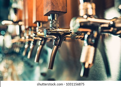 The beer taps in a pub. nobody. Selective focus. Alcohol concept. Vintage style. Beer craft. Bar table. Steel taps. Shiny taps.