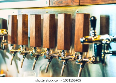 The Beer Taps In A Pub. Nobody. Selective Focus. Alcohol Concept. Vintage Style. Beer Craft. Bar Table. Steel Taps. Shiny Taps.