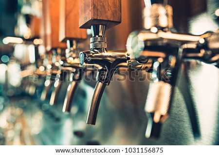 The beer taps in a pub. nobody. Selective focus. Alcohol concept. Vintage style. Beer craft. Bar table. Steel taps. Shiny taps.