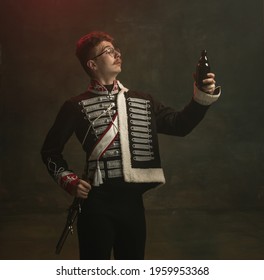 Beer time. Young man in suit as royal person isolated on dark green background. Retro style, comparison of eras concept. Beautiful male model like historical character, monarch, old-fashioned.