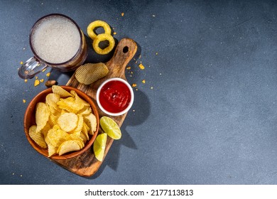 Beer with various salted snacks set. Black table background with traditional party snacks, beer bottles and glasses, with chips, onion rings, salted nuts, crisps and sauces top view copy space - Shutterstock ID 2177113813