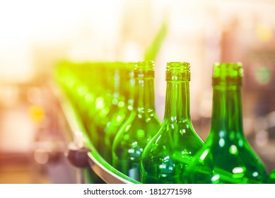 Beer or wine bottles on the conveyor belt. Bottling alkoholic drink. Bottles filled with wine by an industrial machine in a winery factory. 