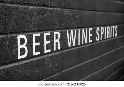 Beer, wine and spirits painted on black wall. White large letters on black. Alcoholic beverage or drink advertisement. Pub, bar, restaurant or wine store background texture. Selective focus on front.