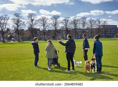 Beeston, Nottingham, Notts, UK. 2nd April 2021. Young Adult Family Group Walking Dogs On Open Ground In March Sunshine