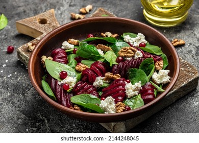 Beet Or Beetroot Salad With Baby Spinach, Cheese, Nuts, Cranberries On Plate With Fork, Dressing And Spices On Dark Background, Food Recipe Background. Close Up.