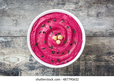Beet hummus in bowl on wooden table

