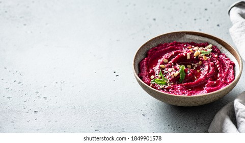 beet hummus in a ceramic bowl on a light background, copy space