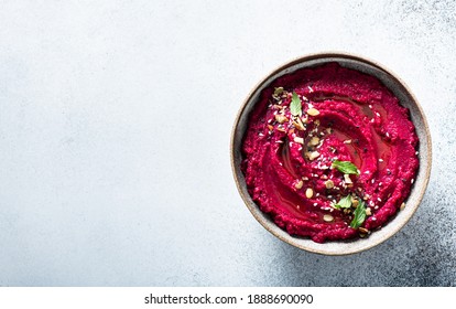 beet hummus in a ceramic bowl on a light background, top view, copy space