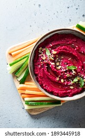 beet hummus in a ceramic bowl on a light background, top view