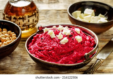 beet hummus and goat cheese on a dark wood background. tinting. selective focus on the middle of hummus