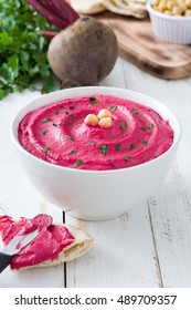 Beet hummus and ingredients on white wooden table

