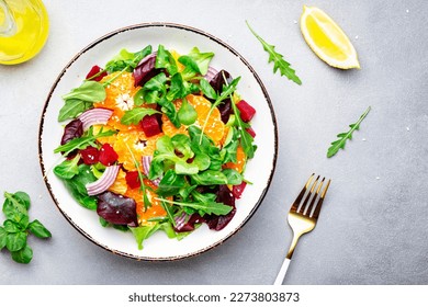 Beet and orange healthy salad with arugula, lamb lettuce, red onion, walnut and tangerine, gray kitchen table. Fresh useful vegan dish for healthy eating - Powered by Shutterstock