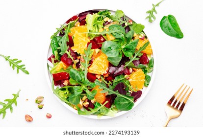 Beet and orange healthy salad with arugula, lamb lettuce, mini chard and pistachios, white kitchen table, copy space. Fresh useful vegan dish for healthy eating - Powered by Shutterstock