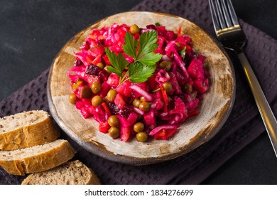 Beet salad in bowl. Healthy detox salad with beetroot, potato, carrot, pickles.Vegetarian vegetable vinegret in a round clay plate on a black background