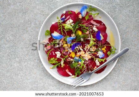 Beet salad with cheese and hazelnut. Shoot close up, in a plate with a fork. Its colourful dish