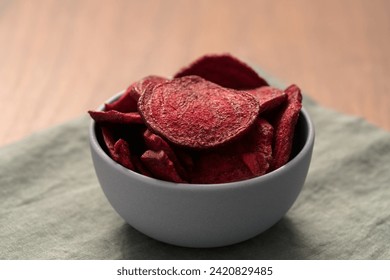 Beetroot chips in ceramic bowl on wooden table with linen napkin - Powered by Shutterstock