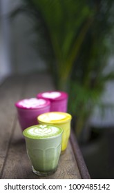 Beetroot, matcha,turmeric lattes are on the wooden table with the palms on the background, Trendy healthy drinks