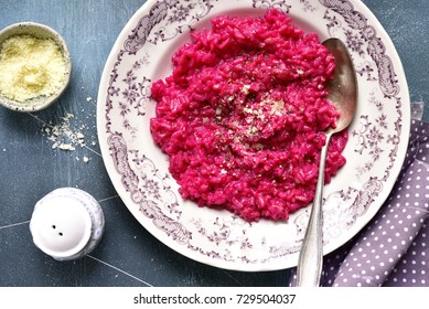 Beetroot risotto with parmesan cheese on a vintage plate over dark blue slate,stone or concrete background.Top view.