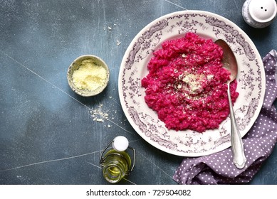 Beetroot risotto with parmesan cheese on a vintage plate over dark blue slate,stone or concrete background.Top view.