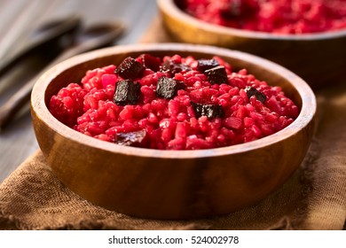 Beetroot risotto prepared with beetroot puree, roasted beetroot pieces on top, photographed with natural light (Selective Focus, Focus in the middle of the risotto)