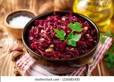 Beetroot salad with wallnuts and garlic in bowl on wooden table. Selective focus.