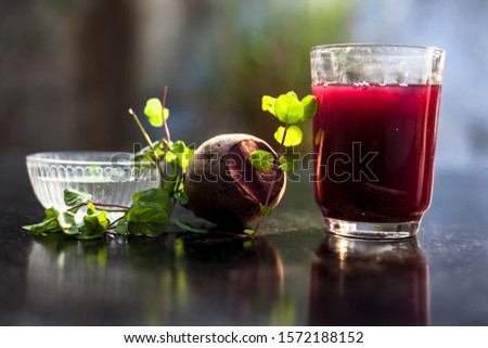 Beetroot smoothie in a glass on black glossy surface with some fresh mint leaves and water.Horizontal shot of beetroot smoothie along with some mint leaves. Shot with blurred background.