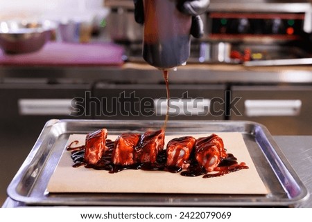 Before baking, the chef pours sauce or marinade over the pork ribs
