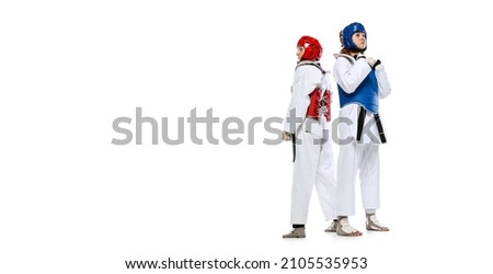 Before fight. Studio shot of of two young women, taekwondo athletes practicing together isolated over white background. Concept of sport, skills. Concept of sport, education, skills, workout, health