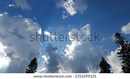 Before a majestic summer thunderstorm, fantastic cumulus clouds adorn the sky above the mountains, a breathtaking scene of nature's power and beauty.