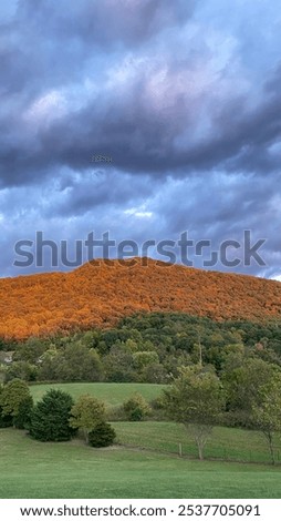 Before the rain: clouds appear on the horizon. A beautiful fall or spring day as the sun paints the open fields and the tops of the Great Smoky Mountains of Eastern Tennessee. Appalachian Mountains.