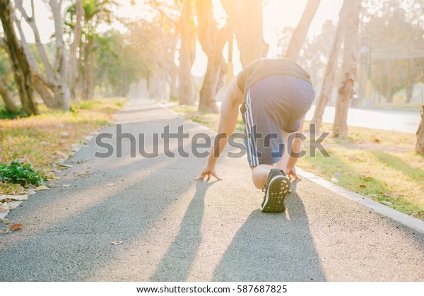 Before the start,Young sports man in start position\
preparing to run